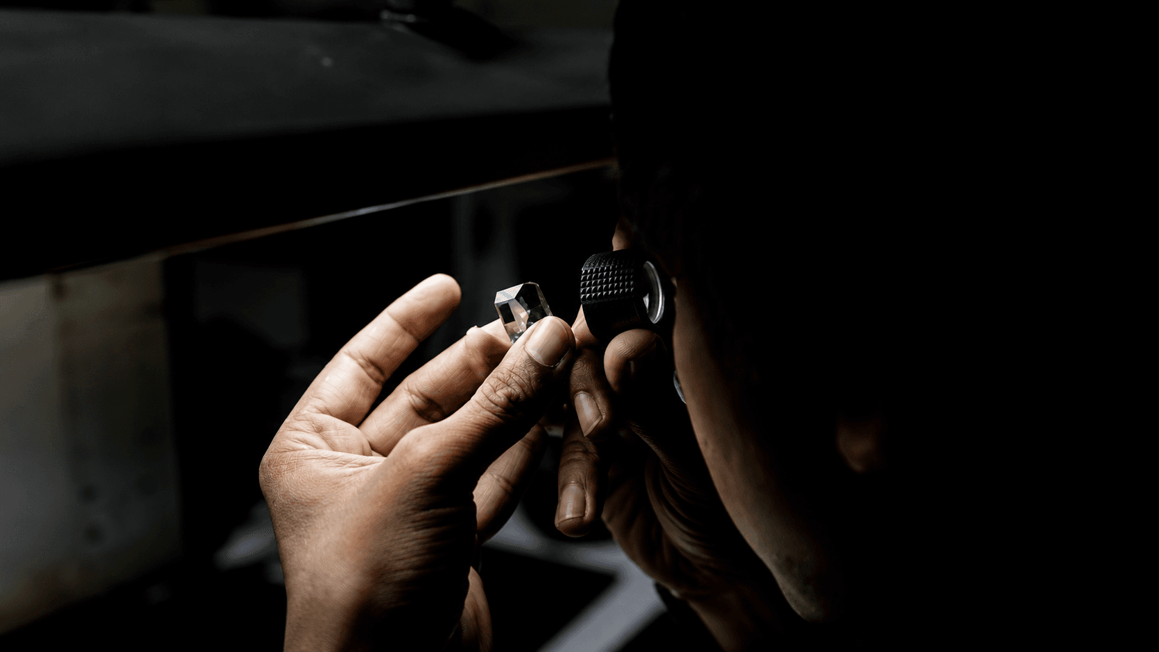 Diamond grader inspecting a lab-grown diamond through a loupe
